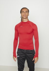 Rotes Langarm-Sporthemd mit taillierter Passform, aus glattem Stoff gefertigt. Verfügt über einen hohen Kragen und ein kleines Logo auf der Brust.