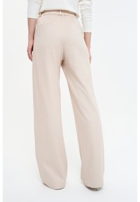 Beigeweit geschnittene Hosen mit einem elastischen Bund und einer Gesäßtasche. Weicher Stoff mit glatter Textur, der für Komfort und Bewegungsfreiheit sorgt.