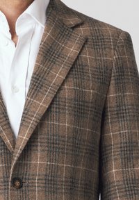 Brązowy marynarka w kratę z niebieskimi i białymi wzorami. Wykonana z teksturowanej tkaniny, z klapami i pojedynczym zapięciem na guzik.