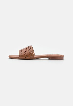 Brun flad slidesandal med bred perforeret læderrem og lav stacket hæl, vist fra siden på en ensfarvet baggrund.