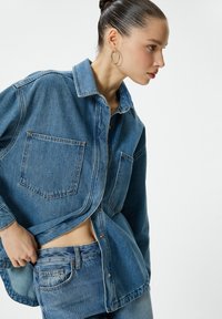 Jeansskjorta i medelblått, med knapp-up front, krage och två påsydda fickor. Mjuk textur med avslappnad passform.