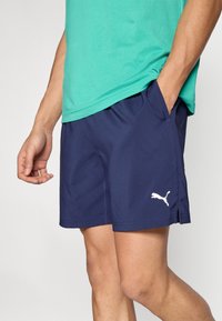 Ναυτικό μπλε αθλητικό σορτς με τσέπες, κατασκευασμένο από λείο, ελαφρύ ύφασμα. Διαθέτει λευκό λογότυπο Puma στο κάτω αριστερό μέρος.