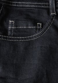 Jeans de mezclilla oscura con un bolsillo frontal, costuras visibles y una textura suave. La tela es duradera y tiene un ligero brillo.