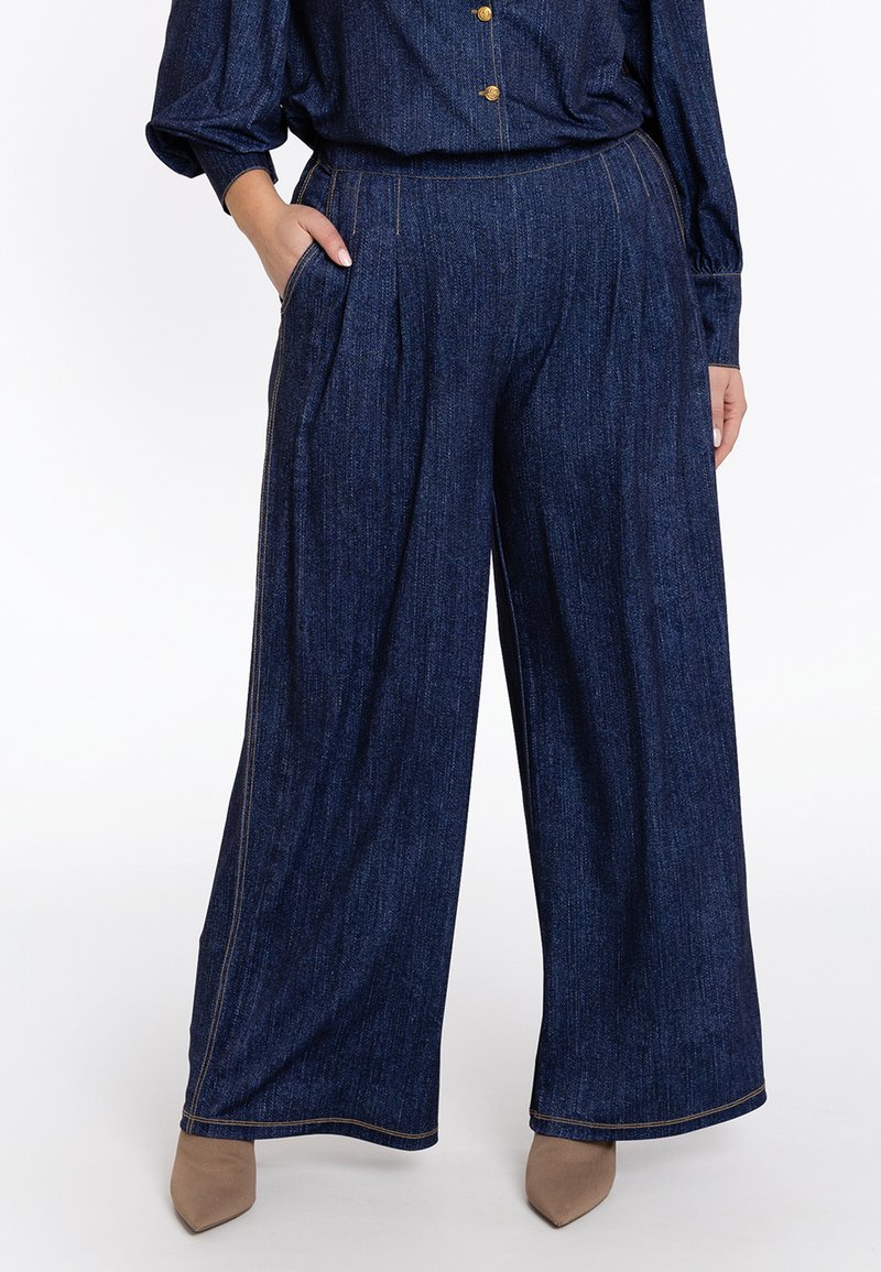 Lange denim broek in donkerblauw met een subtiele geweven textuur, voorzien van zakken en contrasterende beige stiksels.