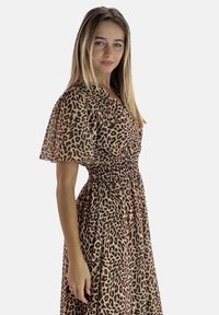 Robe en imprimé léopard avec de courtes manches bouffantes, un décolleté en v, une taille froncée, et une jupe fluide. Fabriquée en un tissu lisse et léger.