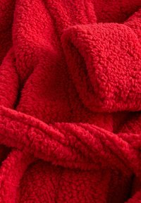 Red, fluffy blanket made of soft, textured fabric. Features thick, looped yarn for added warmth and comfort.