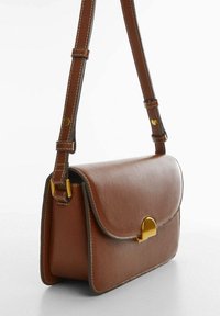 Borsa a tracolla in pelle marrone con chiusura a patta, accessori dorati e cuciture a contrasto. Texture liscia, forma rettangolare, tracolla regolabile.
