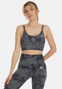 Grijze tie-dye sportbeha van rekbaar materiaal, met dunne verstelbare bandjes en een logo aan de linkerkant. Geshikt met high-waisted legging.