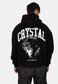 Felpa nera con cappuccio caratterizzata da una grande stampa grafica bianca di un volto di lupo e il testo "CRYSTAL PARIS" sulla schiena. Realizzata in materiale morbido.