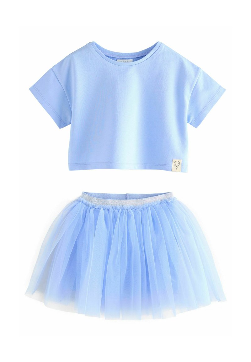 Maglietta cropped azzurra con maniche corte abbinata a una gonna in tulle a strati dello stesso azzurro, dotata di vita elastica.