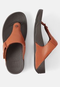 Bruine leren slippers met een gestructureerde donkere rubberen zool, voorzien van een flip-flop ontwerp en een gebrandmerkt logo op de binnenzool.