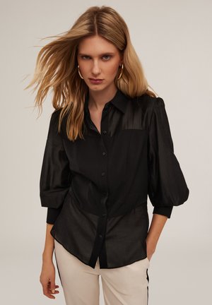 Camicia nera con bottoni, parte superiore strutturata e parte inferiore morbida, dotata di maniche a palloncino 3/4 e una texture liscia e lucida.