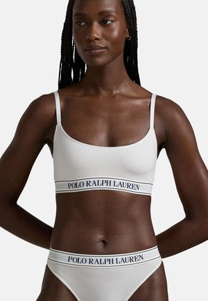 White bralette and matching bikini, made of ribbed fabric, featuring a blue "POLO RALPH LAUREN" waistband. Simple straps and smooth texture.