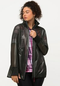 Giacca nera in rete con colletto alto, zip frontale, maniche lunghe e polsini a contrasto. Presenta un design leggero e traspirante.