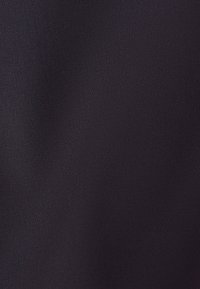 Nærbillede af sort stof med en fin, tæt vævet struktur og subtil lysrefleksion, der skaber en blød gradient.