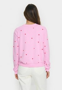 Lichtroze sweatshirt met verspreide rode hartpatronen, lange mouwen, ronde hals en ribgebreide manchetten. Zachte stof met een relaxte pasvorm.