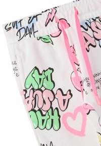 Pantaloni da jogging bianchi con stampe grafiche colorate, dotati di cordini rosa e una texture morbida, che mostrano vari disegni di testo e cartoni animati.
