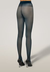 Genomskinliga svarta strumpbyxor med matt yta, en slät midjeresår och en tight passform, i kombination med svarta högklackade skor. Minimal detaljering, lättviktsmaterial.