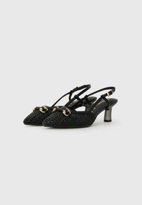 Tacones negros tipo slingback con textura trenzada, punta afilada y dos acentos de hardware en tono dorado. Presentan un tacón de altura media y en ángulo.