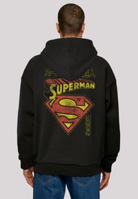 Black hoodie featuring a vintage Superman logo in red and yellow on the back, with Japanese text. Soft fabric, relaxed fit.