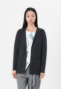 Charcoal gray cardigan with a hood, textured wool blend, open front, and two front pockets, layered over a white shirt with green leaf print.