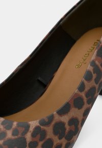 Chaussure plate à imprimé léopard avec une tige synthétique lisse, un bout arrondi et un motif marron et noir, dotée d'une semelle intérieure rembourrée.