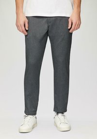 Pantalons tissés gris à coupe slim, avec une légère texture et des poches latérales, associés à des baskets blanches.