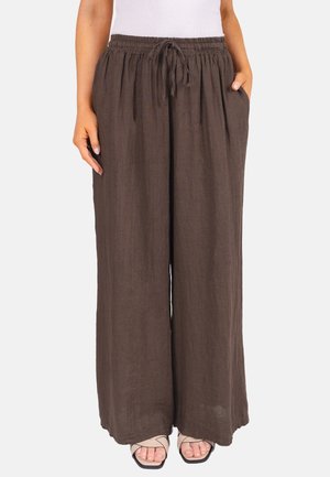 Pantalons larges en lin marron avec taille élastique et cordon de serrage, portés avec un haut blanc et des sandales beiges à bout ouvert.