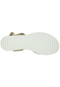 Lichtbeige sandaal met een bovenkant van textuurstof en een witte rubberen zool met horizontale groeven voor grip. Minimalistisch ontwerp.