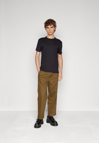 Sort t-shirt kombineret med khaki bukser, der har en afslappet pasform. Båret med sorte snørebåndssko, der fremhæver en robust sål.