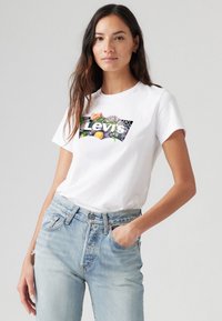 T-shirt en coton blanc avec un graphique coloré du logo floral de Levi's sur le devant. Assorti à un jean taille haute bleu clair.