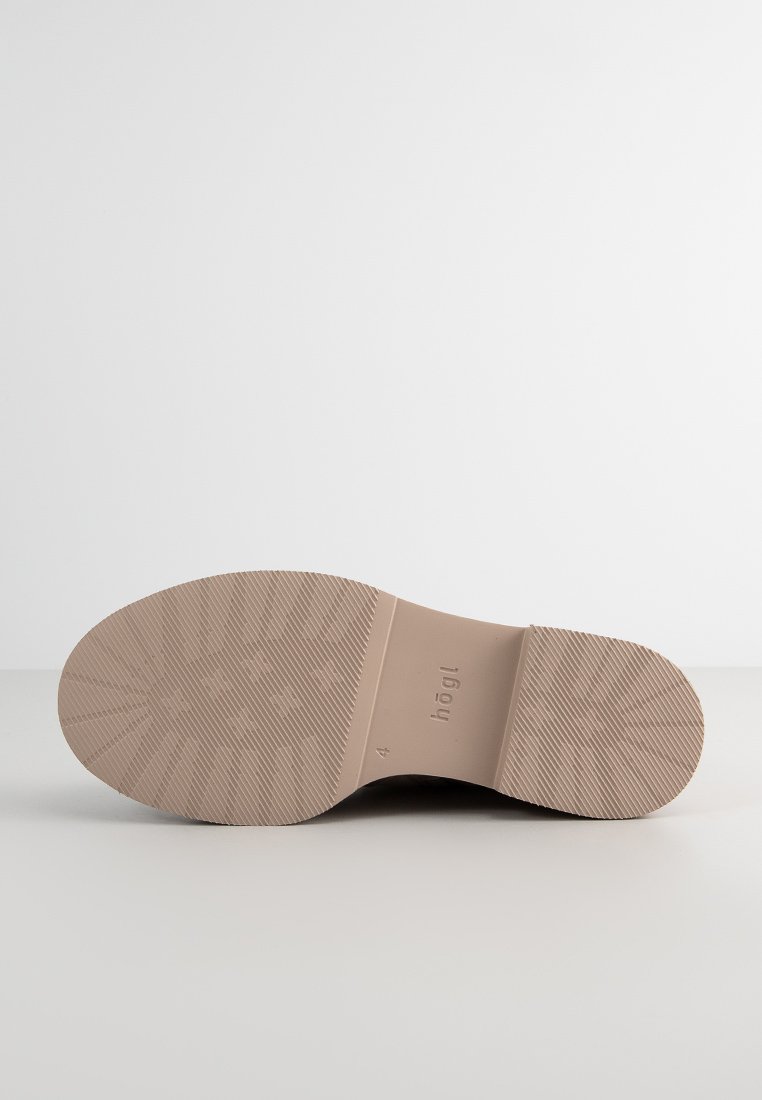 Sohle eines Schuhs aus hellbeigem Gummi mit strukturierten Griffmustern und eingeprägtem Markennamen. Flach, abgerundete Form ohne sichtbare Absatzhöhe.