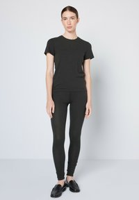 Sötét szürke, testhez simuló póló és leggings, amelyek puha anyagból készültek. A póló rövid ujjú, kerek nyakkivágással és varrat nélküli szélekkel rendelkezik.