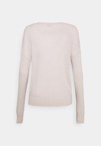 Pull en tricot beige clair à manches longues avec un design simple, coupe légèrement ample et poignets côtelés, vu de dos sur un fond blanc.
