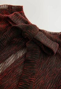 Black and red patterned fabric with a soft, sheer texture. Features a tied bow detail and wavy pleats throughout.