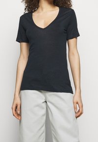 Black short-sleeved V-neck t-shirt with a soft texture, featuring a fitted design and a slightly loose fit at the waist.