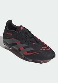 Black soccer cleat with red accents, textured upper, three black stripes, and molded studs for traction. Features laces and a reinforced toe.