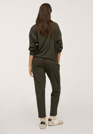 Sweat-shirt vert olive et pantalon de jogging assorti en tissu doux, offrant une coupe décontractée et des poignets côtelés. Complété par des baskets neutres.
