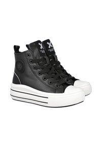 Zapatillas altas de cuero negro con suelas de goma blanca, que presentan cordones negros, un logo redondo en el lateral y una puntera blanca en contraste.