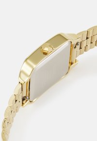 Montre en or avec un boîtier rectangulaire, couronne hexagonale et bracelet en maillons métalliques. Fini poli avec une texture lisse.