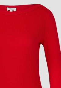 Haut rouge côtelé avec manches longues et décolleté large. Confectionné en tissu extensible, présentant une texture minimale et sans motifs visibles.