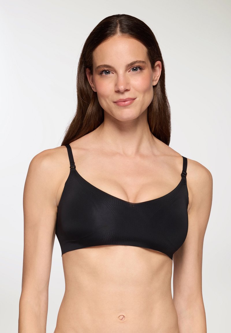 Reggiseno wireless nero con spalline regolabili, texture liscia e design a pattern sottile. Presenta un collo arrotondato e uno stile minimalista.