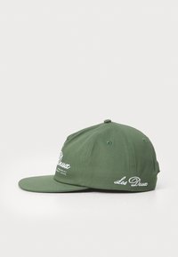 Casquette verte en coton, avec une visière plate, logo brodé à l'avant et sur le côté, et œillets de ventilation en métal.