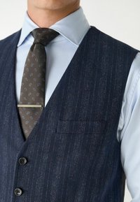 Marineblauw gestreepte gilet van textuurstof, voorzien van een enkel borstzakje en drie knopen, gecombineerd met een lichtblauw dresshirt en een gestreepte stropdas.