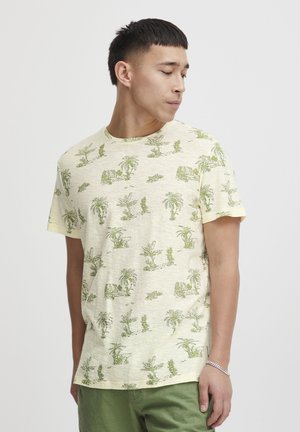 Light yellow short-sleeve t-shirt featuring a botanical green print of plants and rocks. Soft texture and relaxed fit.