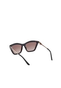 Gafas de sol de estilo cat-eye en color negro con lentes marrones degradados, con acentos de hardware dorado texturizado y patillas brillantes negras.