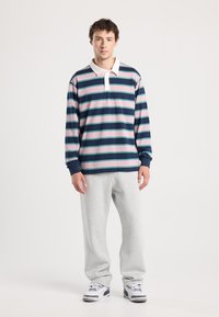 Raitapaita tummansinisessä, vaaleanpunaisessa ja teal-värissä, valkoisella kauluksella. Yhdistetty harmaisiin verkkareihin ja valkoisiin lenkkareihin. Rentoa tyyliä.