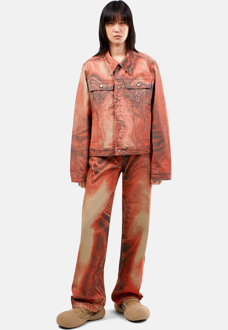 Setti denim-takkia ja housuja, jossa on kieppuva punainen ja vaaleanruskea kuvio. Varustettu kahdella rintataskulla ja pehmeillä ruskeilla liukuvilla kengillä.