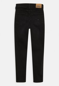 Jeans ajustados negros con una cintura alta, hechos de denim, que cuentan con dos bolsillos traseros y una etiqueta de cuero marrón con el logo de la marca.