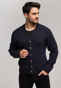Granatowy wełniany kardigan z dekoltem w serek, z przodem zapinanym na guziki, prążkowanymi mankietami i dwoma bocznymi kieszeniami.